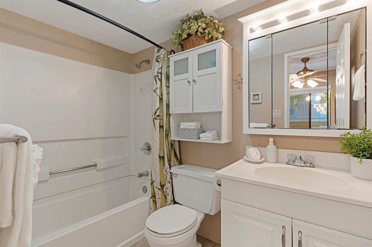 Een badkamer met een bad, toilet en een wastafel met spiegel.