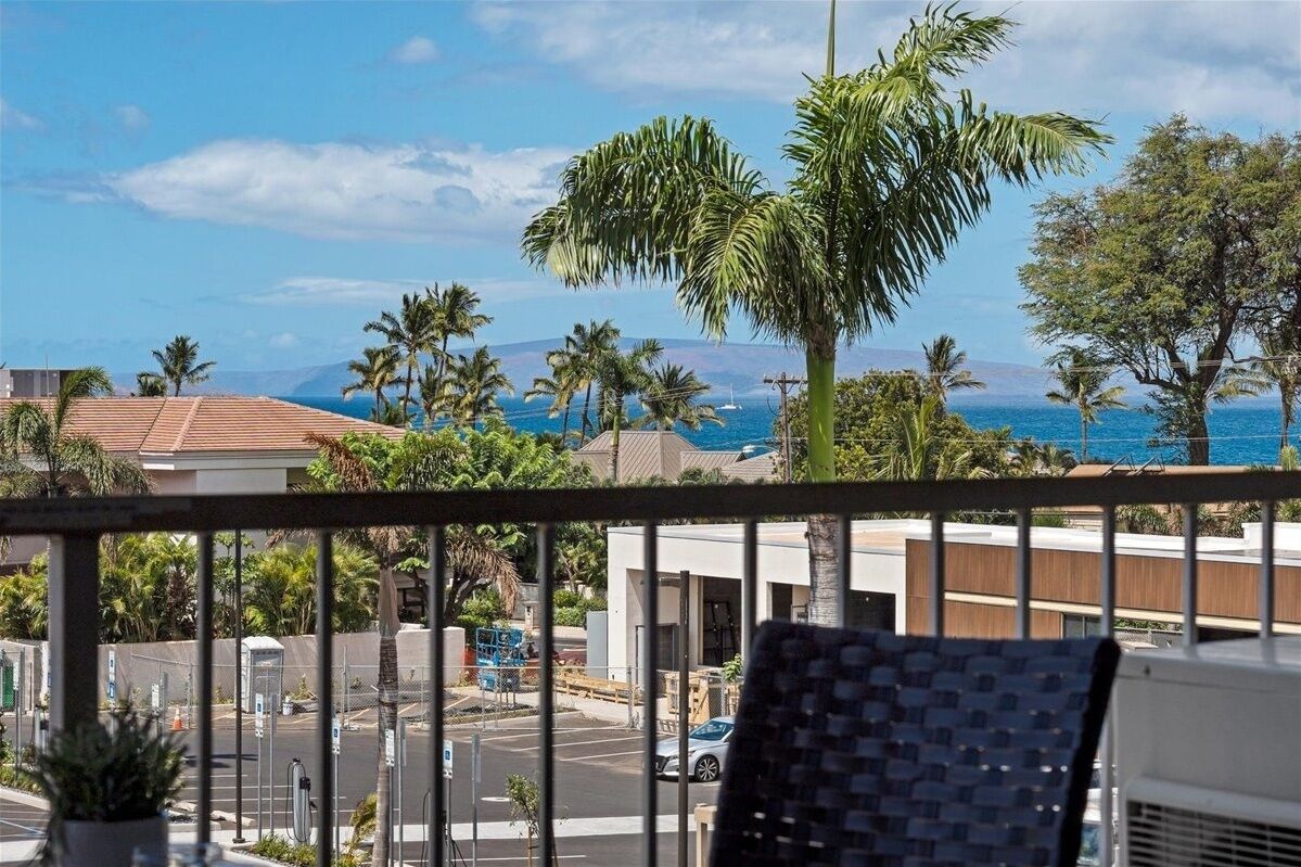 A balcony with a view of the ocean and palm trees.