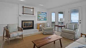 A living room with a fireplace, two armchairs, a sofa, and a wooden coffee table. - Highsmith Cottage (Oceanfront Home) (Atlantic Beach)