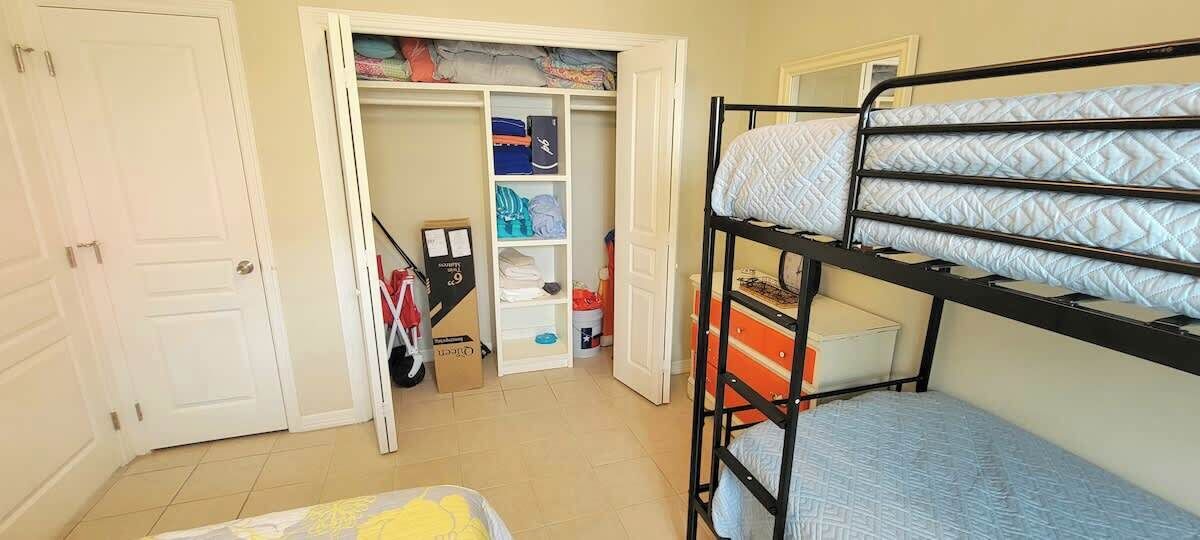 A bunk bed room with a closet containing folded clothes and a cardboard box.