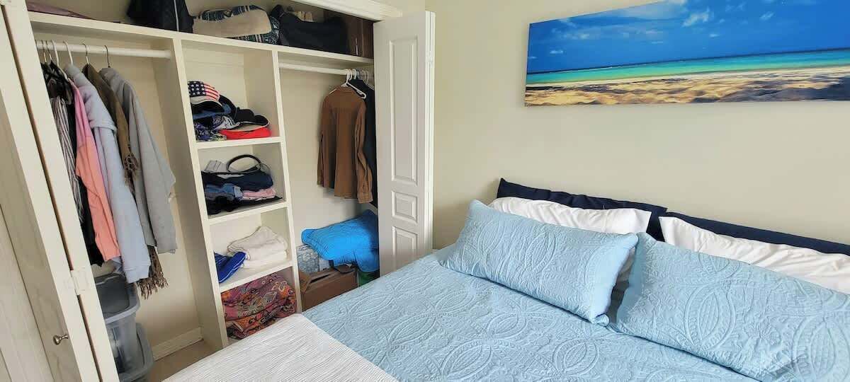 Une chambre à coucher avec un lit, une armoire et un tableau représentant une plage.