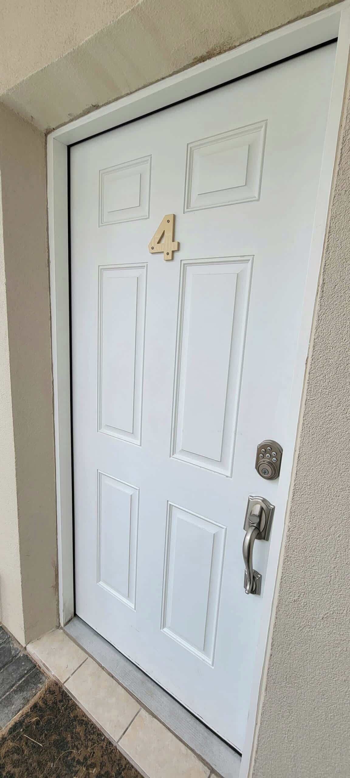 Una puerta blanca con el número 4, un teclado electrónico de seguridad y un picaporte.