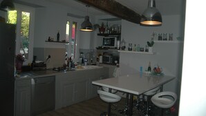 Una cocina moderna con armarios blancos, una isla central, iluminación colgante y un comedor con taburetes de bar.