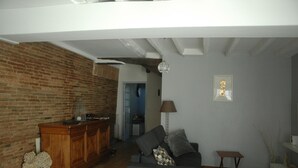 Una sala de estar con una pared de ladrillo, un mueble de madera, un sofá gris y una mesita.