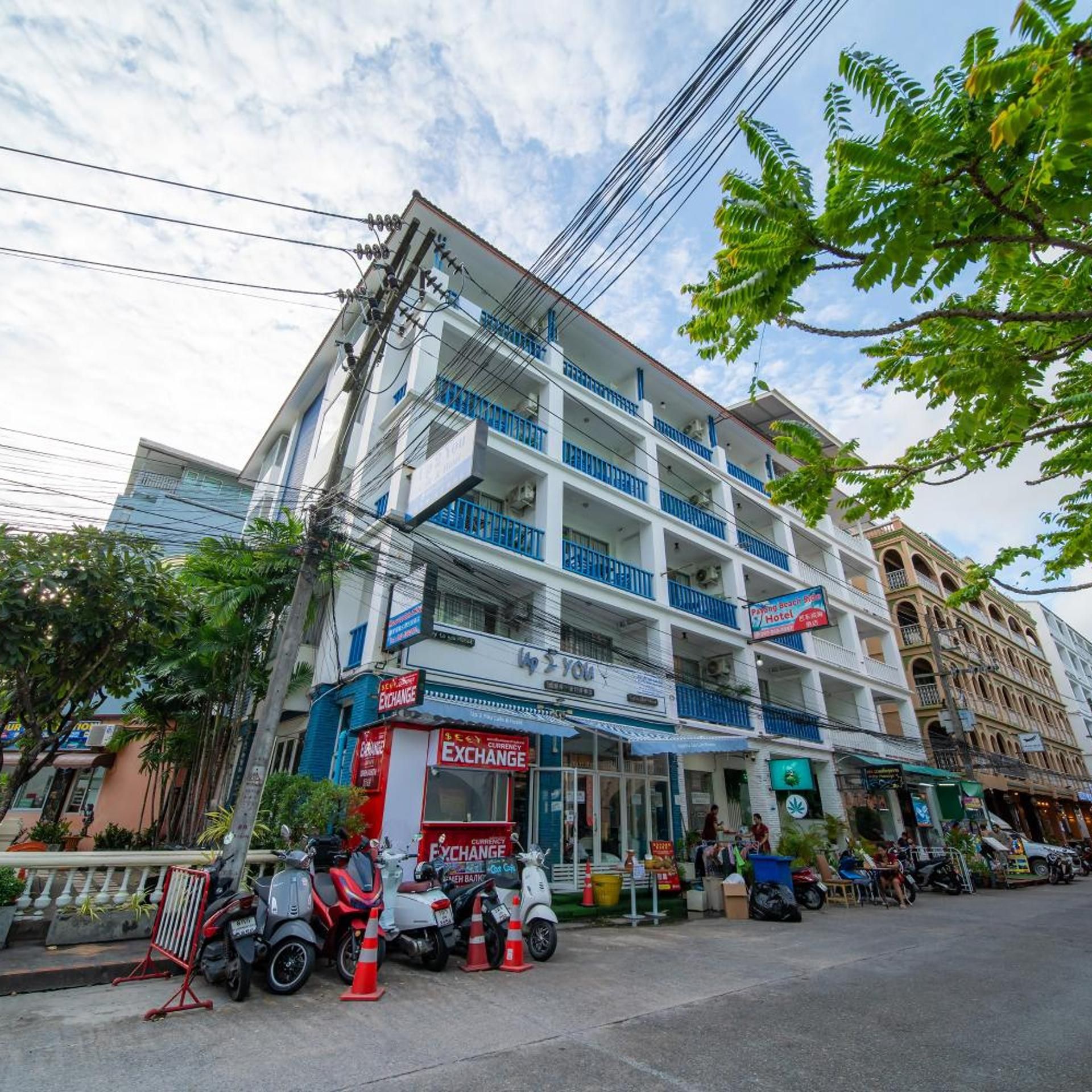 A multi-story building with balconies, a currency exchange shop on the ground floor, and a hotel sign.