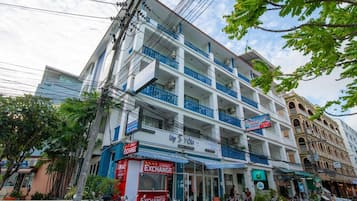 A multi-story building with balconies, a currency exchange shop on the ground floor, and a hotel sign.