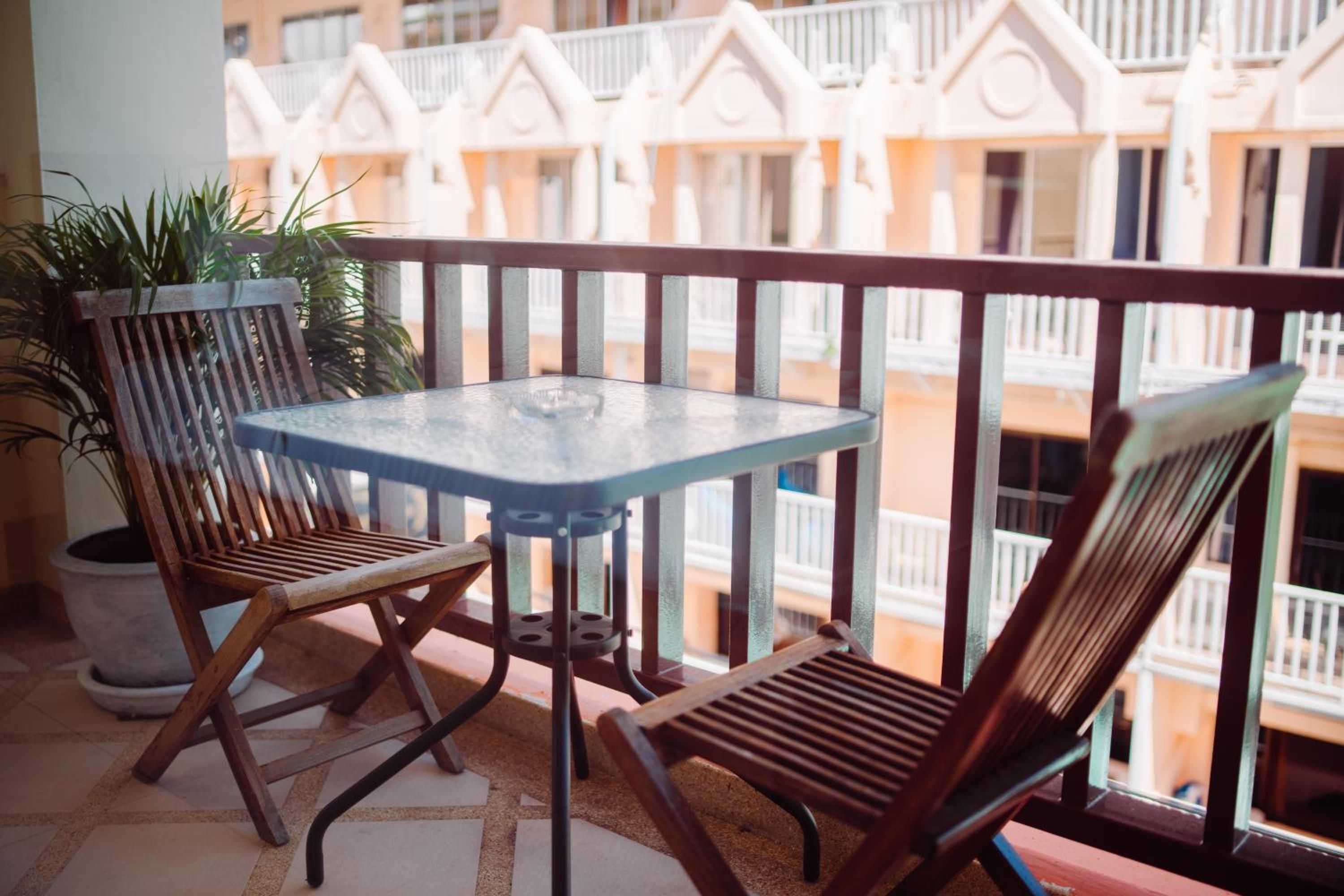 A balcony with a glass table and two wooden chairs.