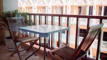 A balcony with a glass table and two wooden chairs.