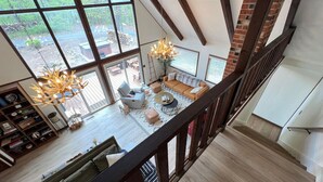 Een ruime loft met hoge plafonds, grote ramen en een moderne trap.