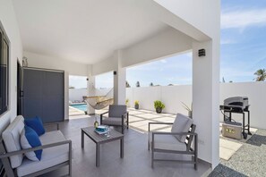 Eine moderne Außenpatio mit Blick auf einen Pool, einem Sitzbereich und Grillmöbel.