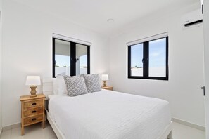 A bedroom with a bed, two bedside tables, a window, and a door. - Aruba Getaway: Luxe Villa, 3BR near Beach (Oranjestad)