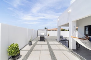 Eine Terrasse mit Grill, Sitzgelegenheiten und einer Hängematte.