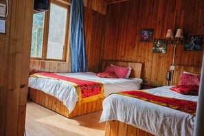 Eine Holzhütte mit zwei Betten, einem Vorhangfenster und Wandlampen.