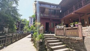 Ein traditionelles Gebäude mit einem hölzernen Balkon und Steinstufen, die zum Eingang führen.