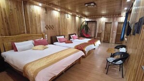 Ein Zimmer mit Holzwänden, drei Betten, einem Hängesessel und einem kleinen Tisch.