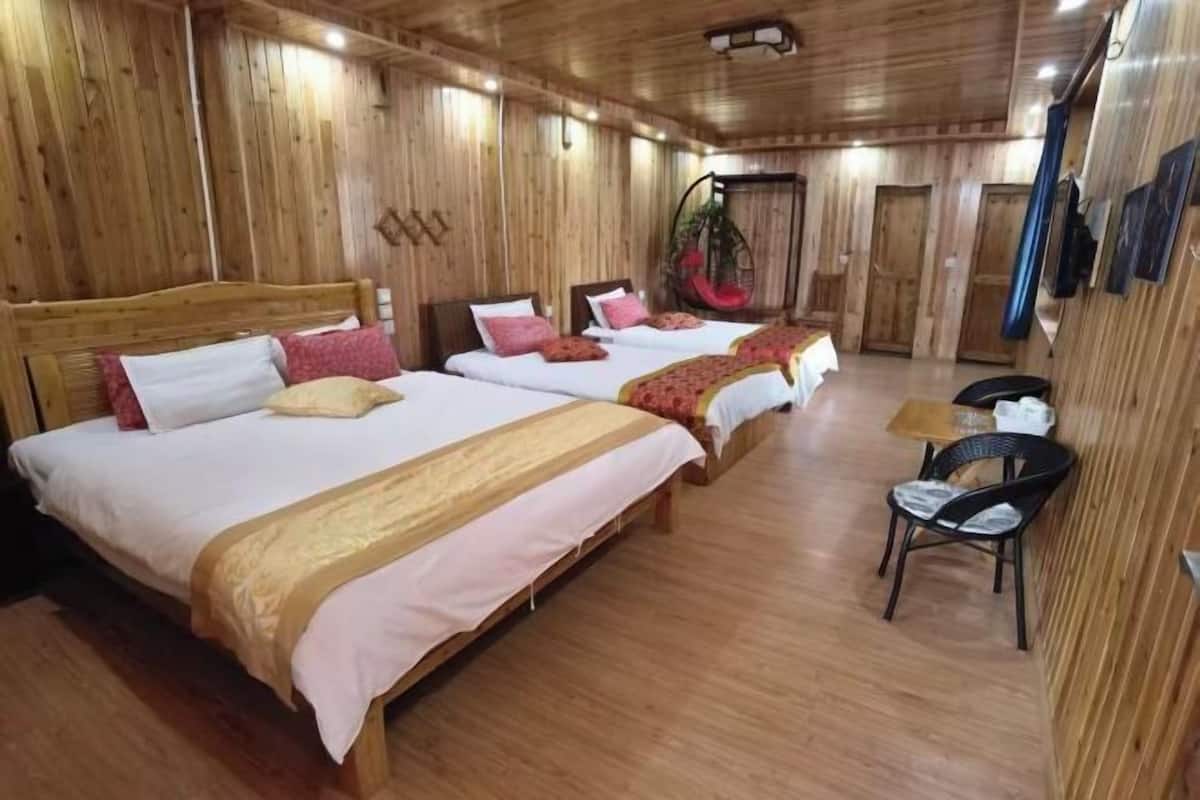 A wooden-paneled room with three beds, a hanging chair, and a small table.