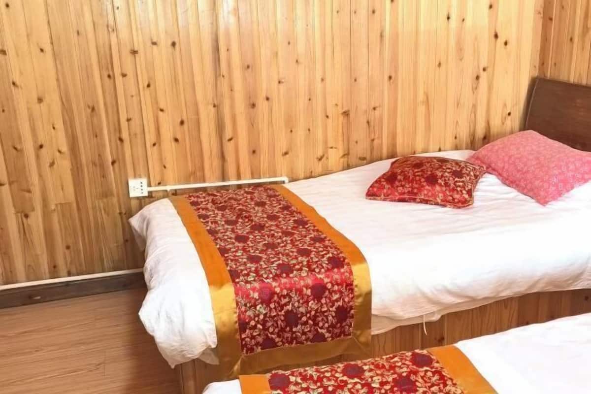 A room with two beds, wooden walls, and a power outlet on the wall.