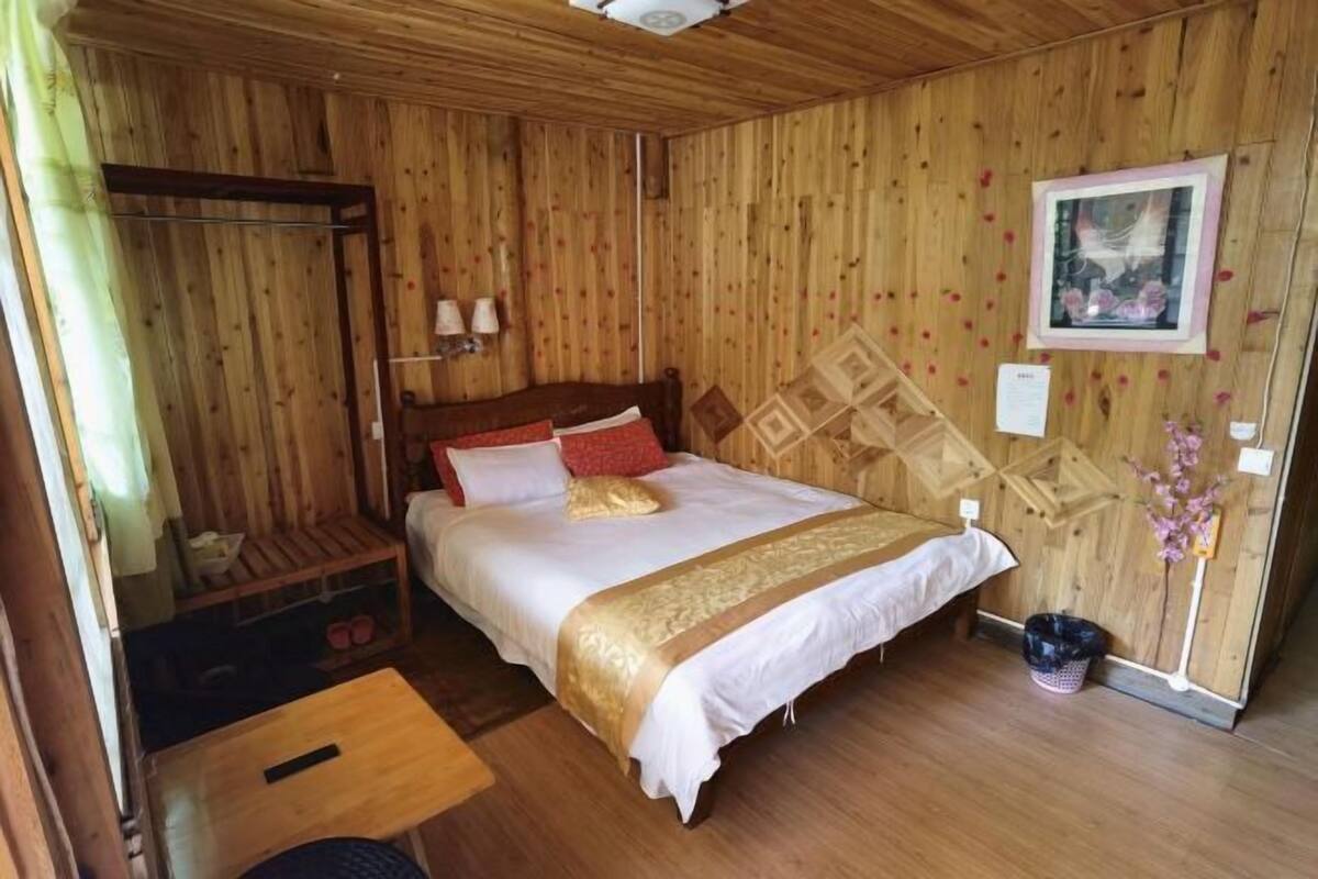 A wooden-paneled room with a bed, a small table, and a bench.