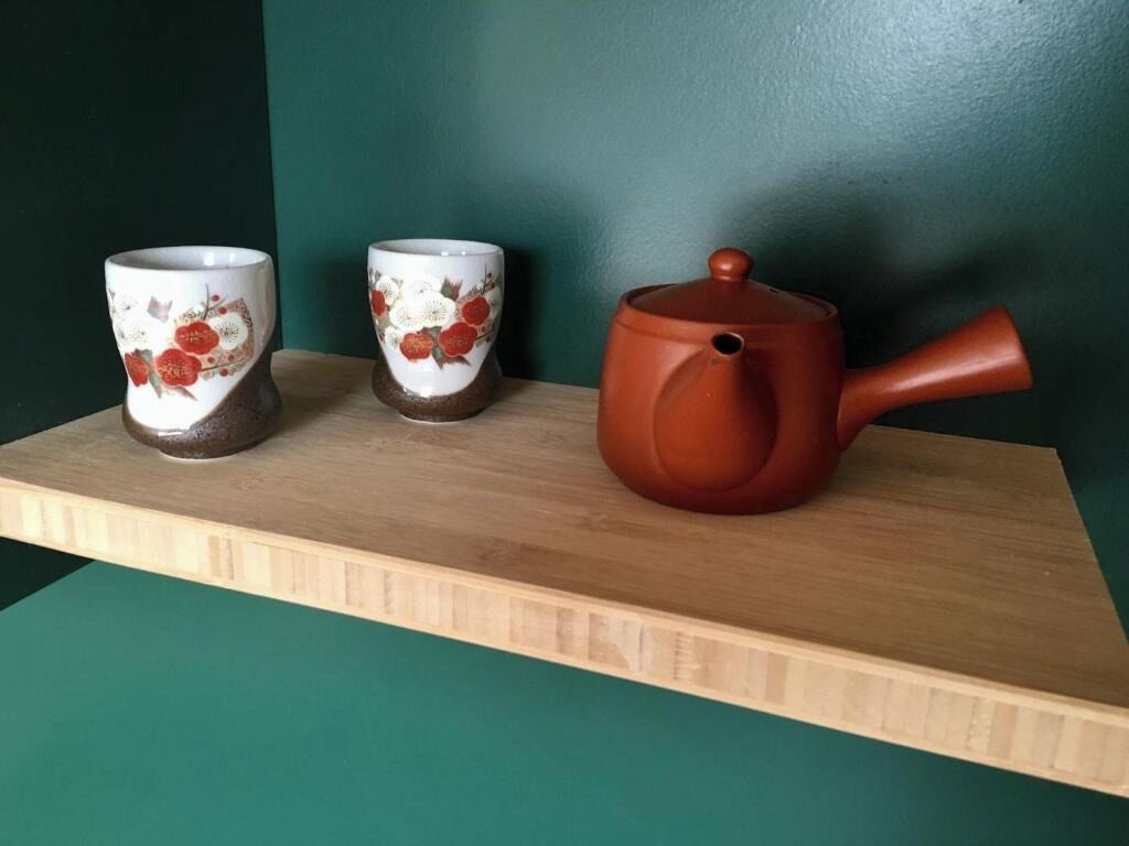 A shelf with two ceramic cups and a teapot.
