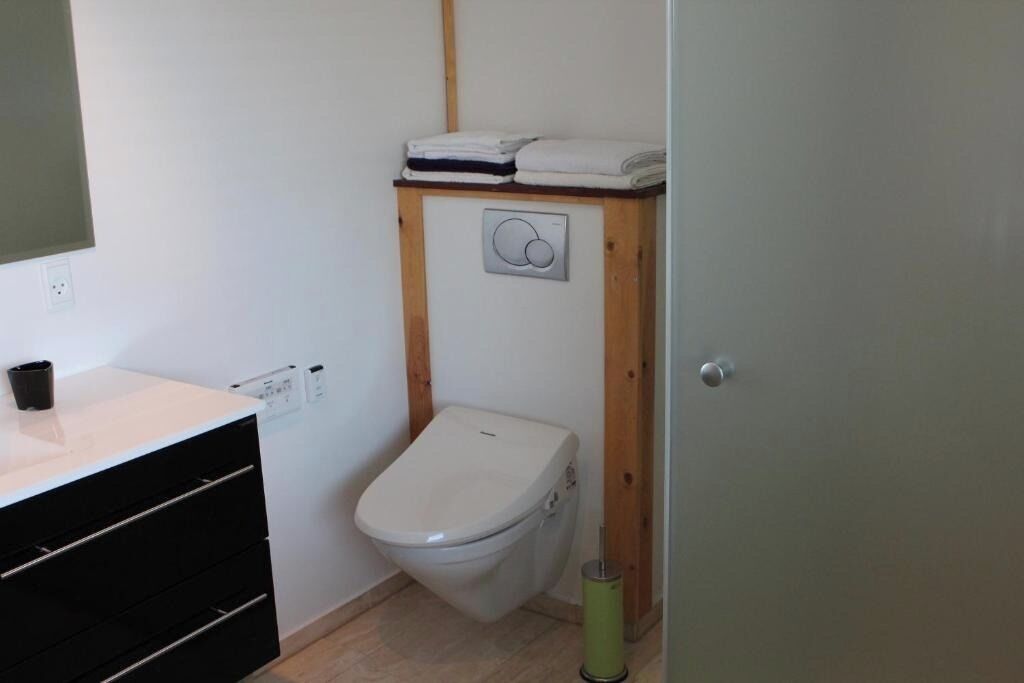 Ein kleines, kompaktes Badezimmer mit Toilette, Waschbecken mit Spiegel und Ablagefläche mit gefalteten Handtüchern.