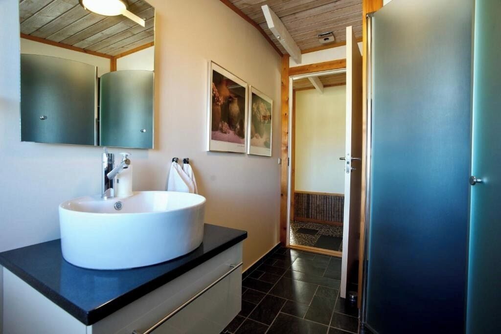 Un baño moderno con un lavamanos grande de color blanco, un espejo y dos cuadros enmarcados en la pared.