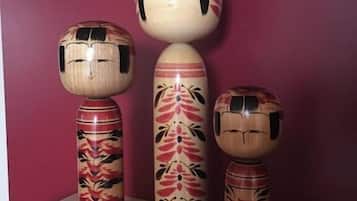 Tres figuras de madera con motivos florales sobre una mesa frente a una pared rosa.