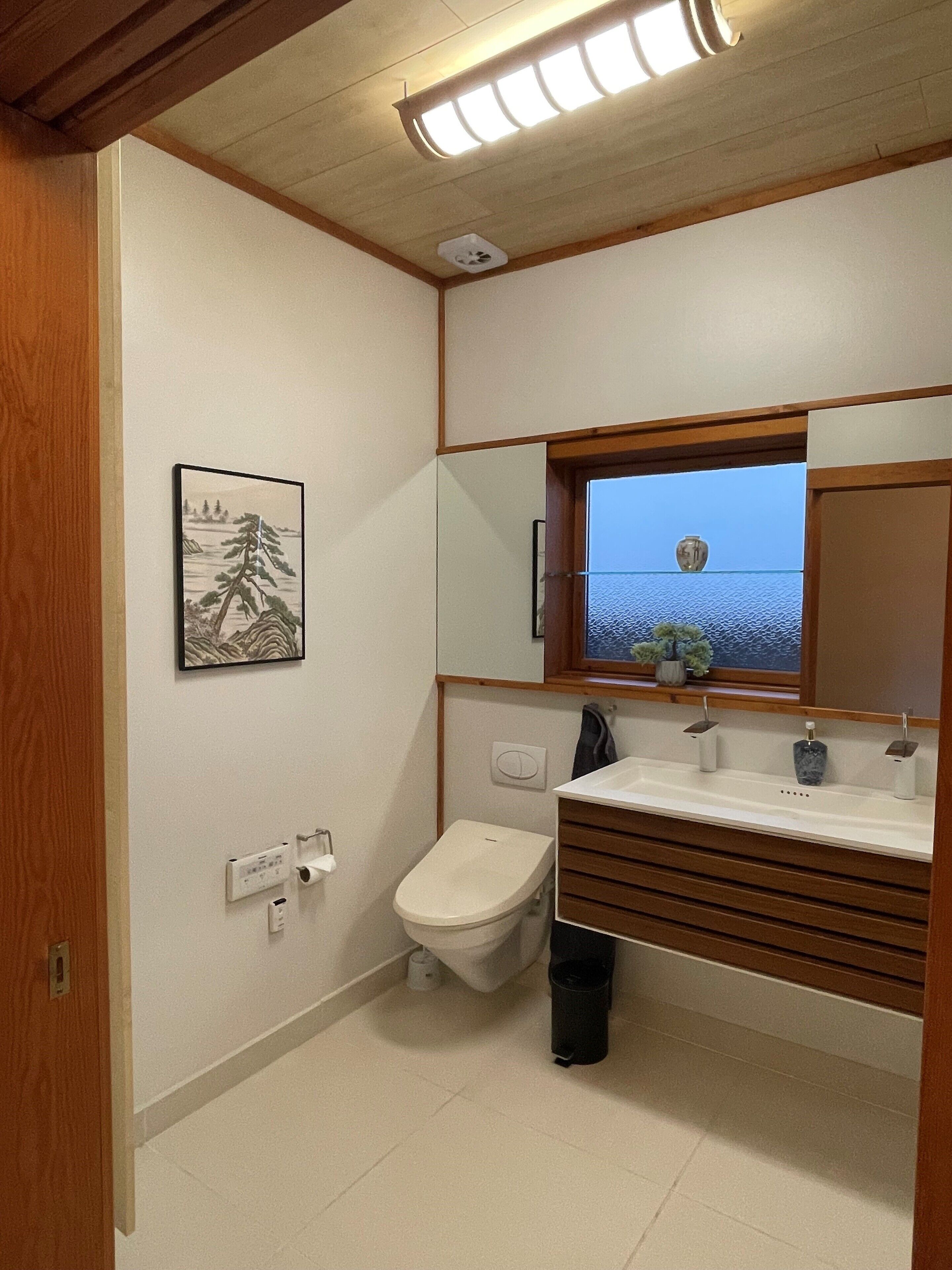 Ein Badezimmer mit Toilette, Waschbecken, Spiegel und einem gerahmten Bild an der Wand.