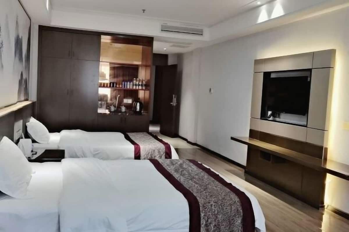 Hotellihuone, jossa on kaksi sänkyä, minibaari, televisio ja suuri peili.
