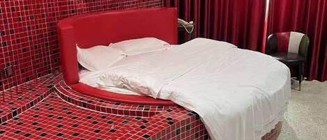 A bed with a red headboard in a room with a red and black checkered floor pattern.