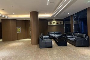 A modern lobby with leather seating, a large pillar, and a framed artwork on the wall. - Poyang Yishang · Wanjing Business Hotel (Poyang)