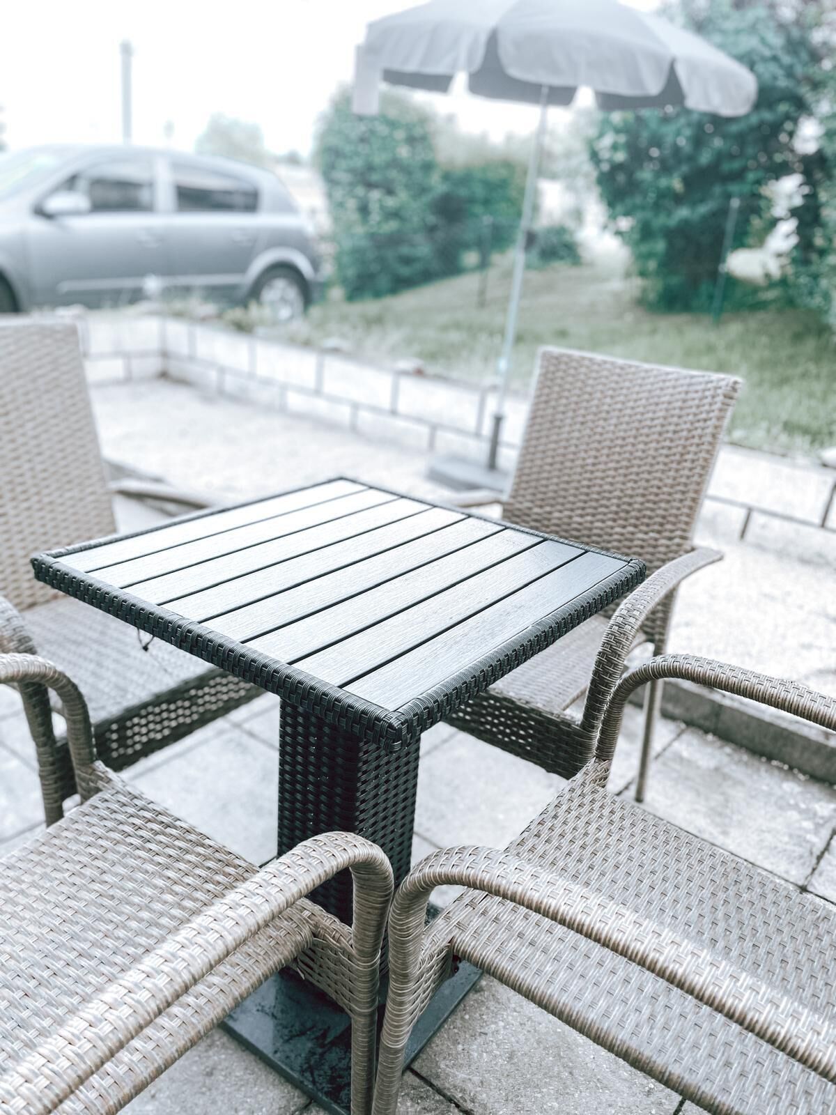 Una mesa cuadrada con una silla de mimbre trenzado.