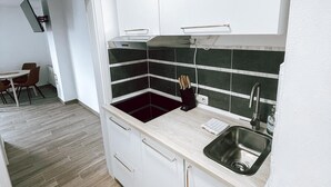 Una cocina moderna con armarios blancos, un salpicadero blanco y negro y un lavamanos de acero inoxidable.