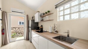 Eine moderne Küche mit Spüle, einem Fenster mit Milchglas und einer Tür, die auf einen Balkon führt.