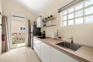 Une cuisine moderne dotée d’un évier encastré, d’une fenêtre à vitre dépolie et d’une porte donnant sur un balcon.