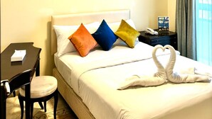 Habitación de hotel con cama, escritorio y silla. Hay un cartel en el escritorio y un teléfono en la mesita de noche.