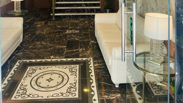 Un vestíbulo de hotel con suelo de mármol, una escalera y un mostrador de recepción.
