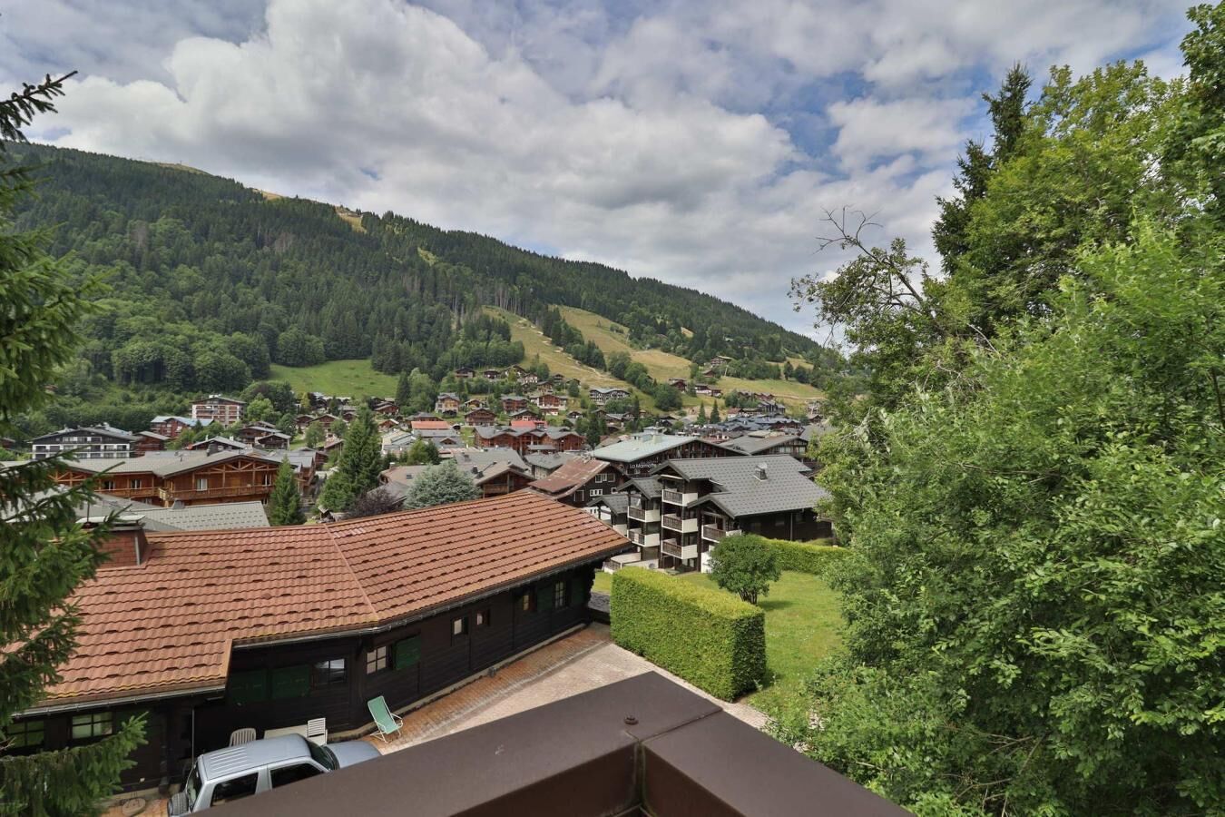 A mountain village with traditional wooden houses, a clear view of the valley, and a lush green landscape.