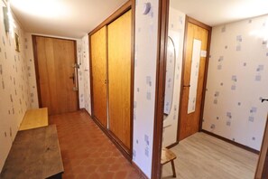 Un pasillo con puertas de madera, suelo de baldosas y un taburete pequeño.