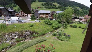 Un quartiere residenziale con case, un ruscello e un piccolo giardino fiorito.