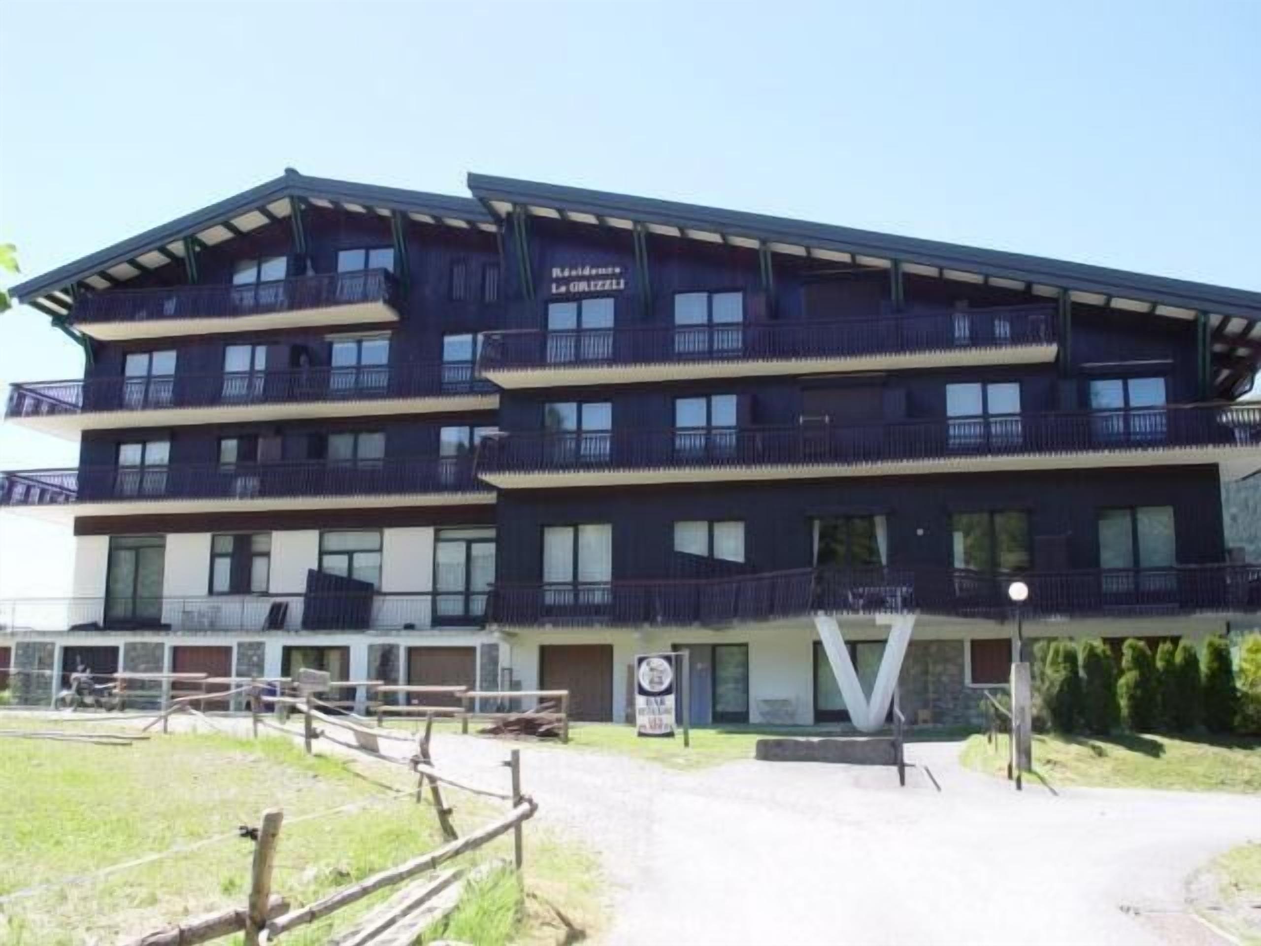 A multi-story hotel with balconies, a parking area, and a sign indicating a restaurant.