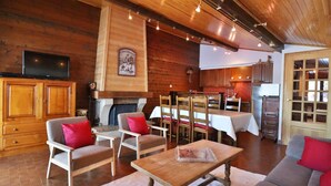 Un accogliente interno di una baita con pareti in legno, un camino, un'area da pranzo e una cucina.