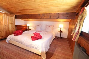 A wooden-paneled bedroom with a bed, two bedside lamps, and a window with a curtain.