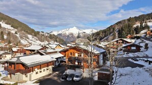 Un villaggio innevato con case in legno tradizionali, una chiesa e montagne sullo sfondo.