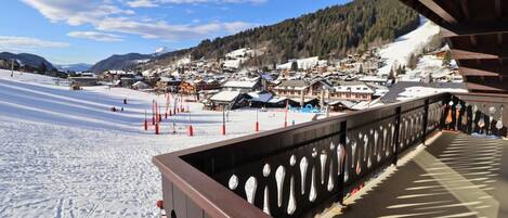 A snow-covered ski resort with a wooden deck overlooking the area.