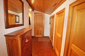 A hallway with wooden doors, a wooden dresser, and a mirror on the wall.