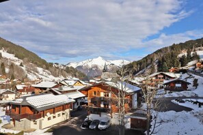 A snow-covered village with traditional wooden houses, a church, and a mountain backdrop.