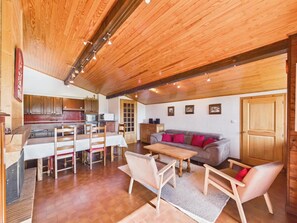 A spacious living area with a wooden ceiling, a sofa set, and a dining table.