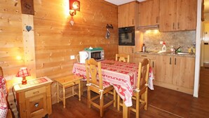 Una cabaña de madera acogedora con una mesa de comedor preparada para cuatro personas, un microondas y una estufa en la zona de cocina.