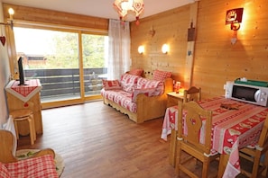 A cozy room with a bed, a desk, and a dining table. There is a window with a view of trees. - 300m from resort center, 1st floor, balcony, ski locker, 30m², Les Gets (Les Gets)