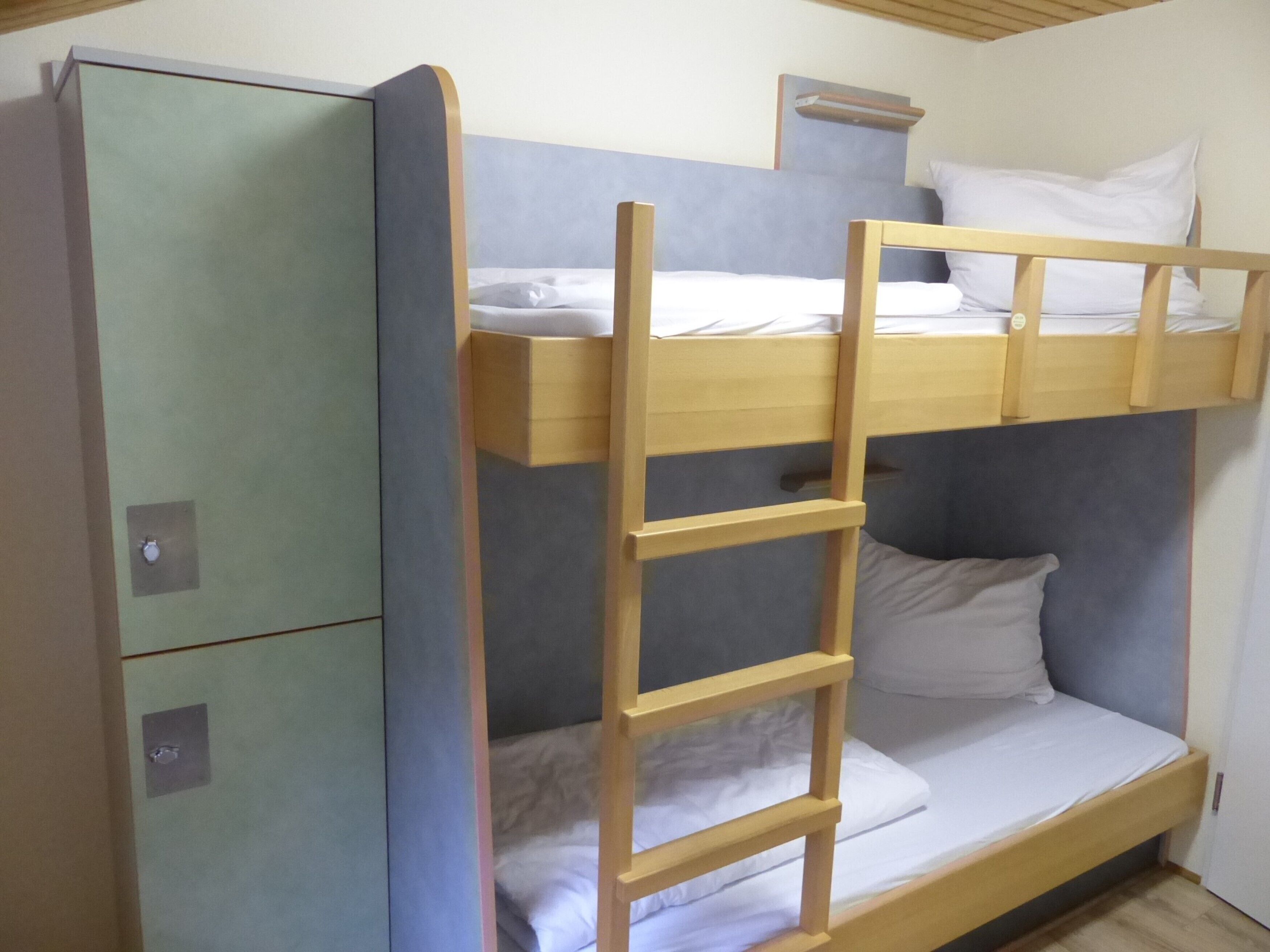 Ein Etagenbett mit einer Leiter, einem Kleiderschrank und einem Regal darüber.